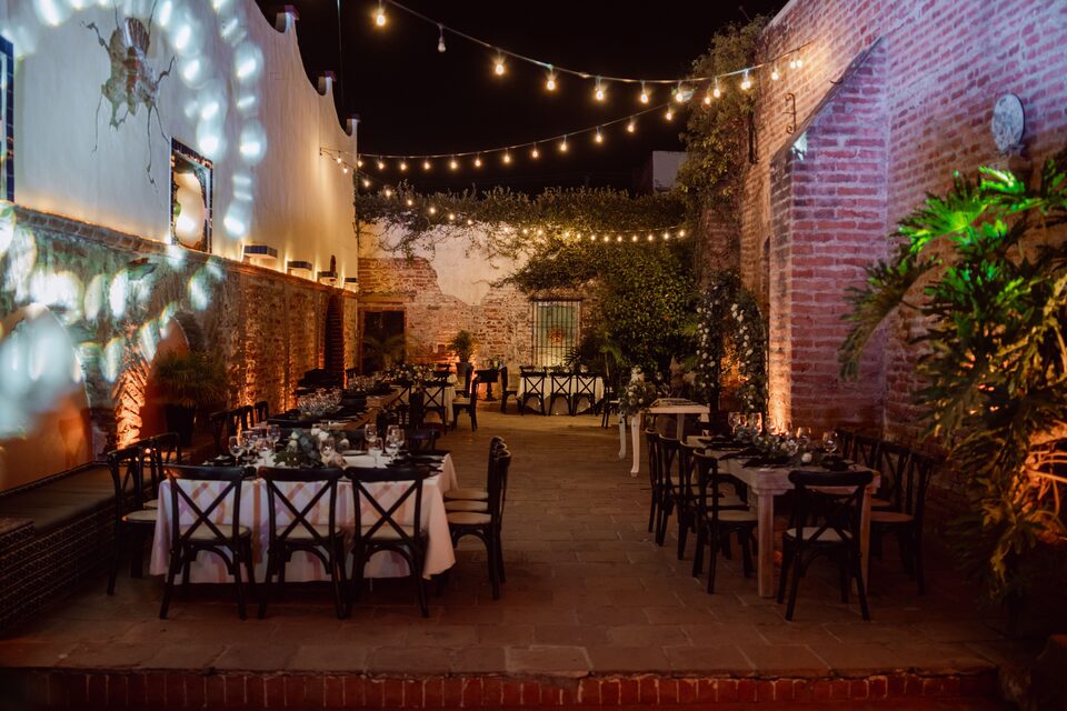 An evening reception set with tables under strings of warm lights.